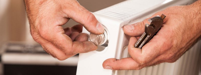 Close up image of a plumbing engineer tightening a bolt on a radiator.